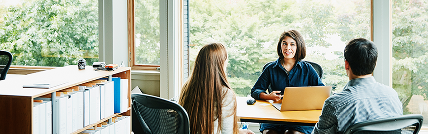 Woman sitting at desk talking with a couple