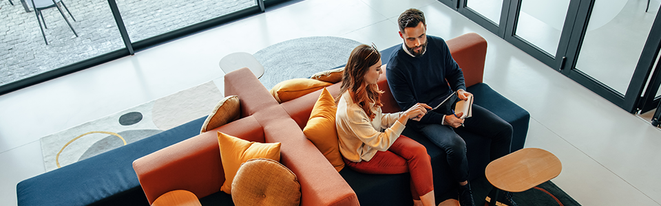 Woman and man sitting on couch looking at a tablet